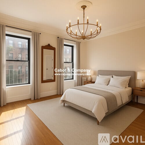 A bedroom with a large bed, a chandelier, and a view of a city street through the windows.