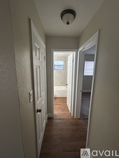 A hallway with white walls and wooden floors.
