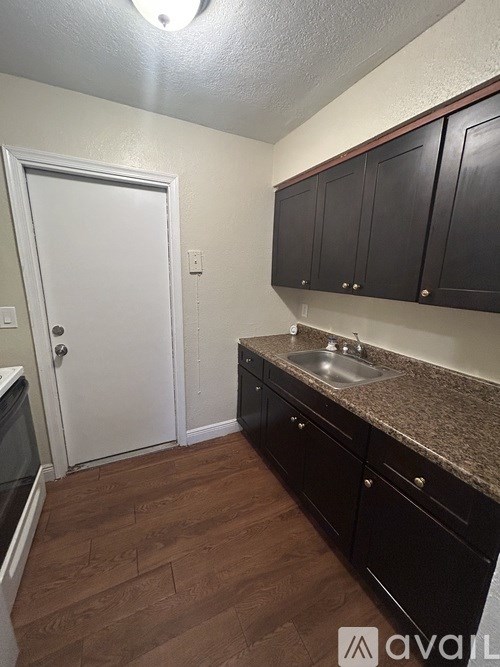 A kitchen with black cabinets and a white door.