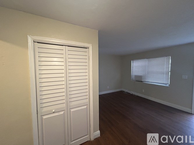 A room with a white door and a window with blinds.