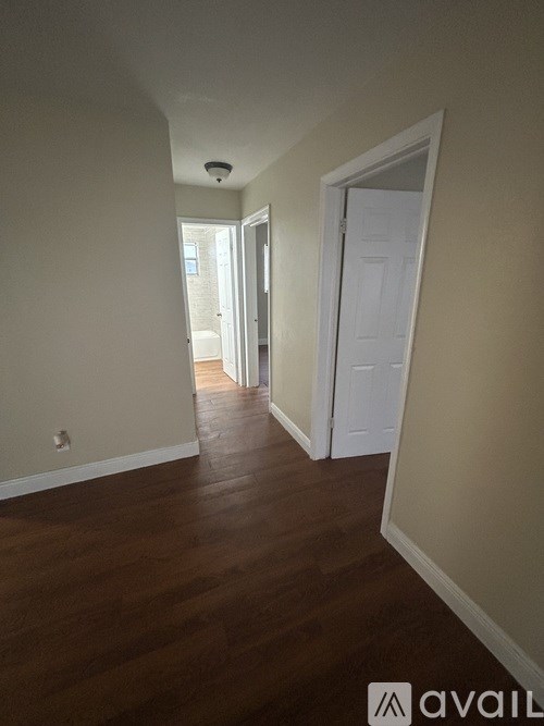 A hallway with a white door and wooden floors.