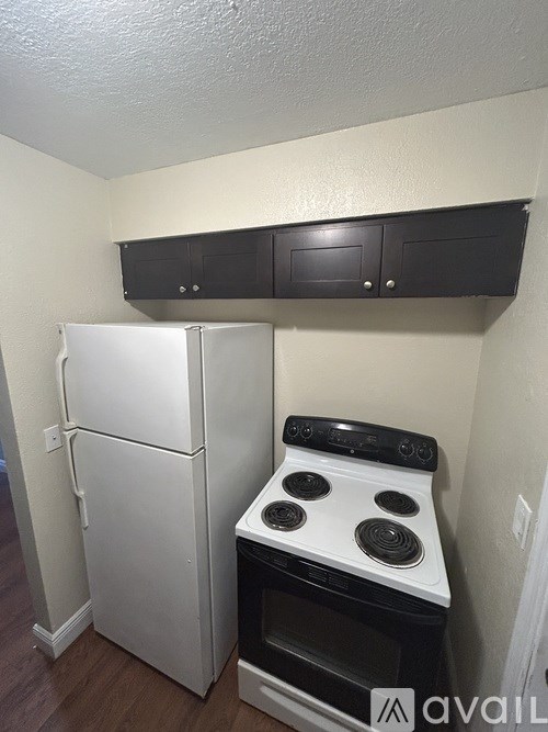 A white refrigerator and a black stove top oven in a small kitchen.