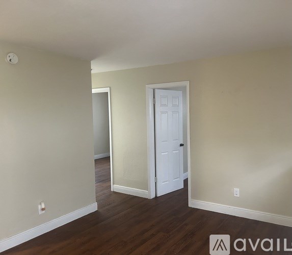 A room with a white door and wooden floors.