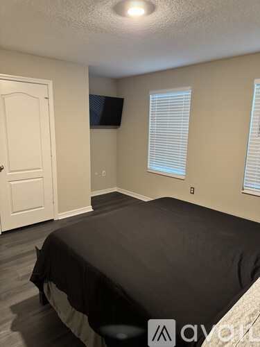 A bedroom with a bed, a door, and a window with blinds.