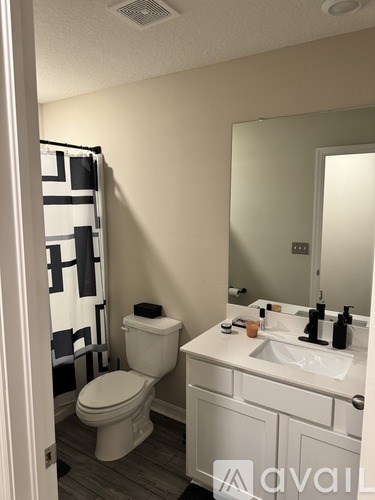 A bathroom with a toilet, sink, and mirror.