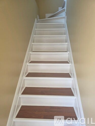A set of stairs with white risers and brown treads.