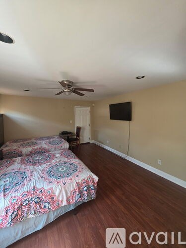 A bedroom with a bed, a ceiling fan, and a television.