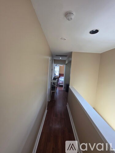 A long hallway with a wooden floor and white walls.
