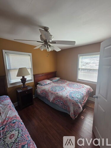 A bedroom with a bed, a ceiling fan, and a window with blinds.