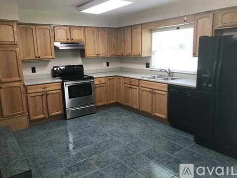 A kitchen with wooden cabinets and a black refrigerator.