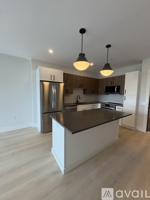 A modern kitchen with a center island and pendant lights.