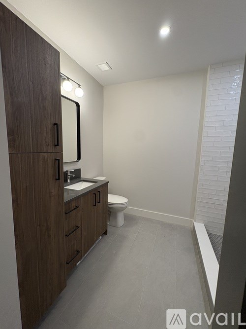 A bathroom with a toilet, sink, and mirror.