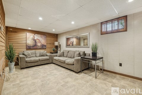 A living room with a couch, chair, and a painting on the wall.