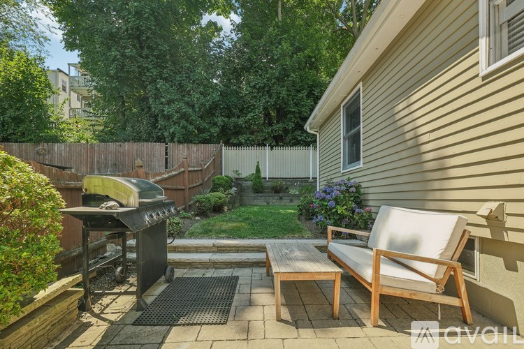A backyard with a grill and a lounge chair.
