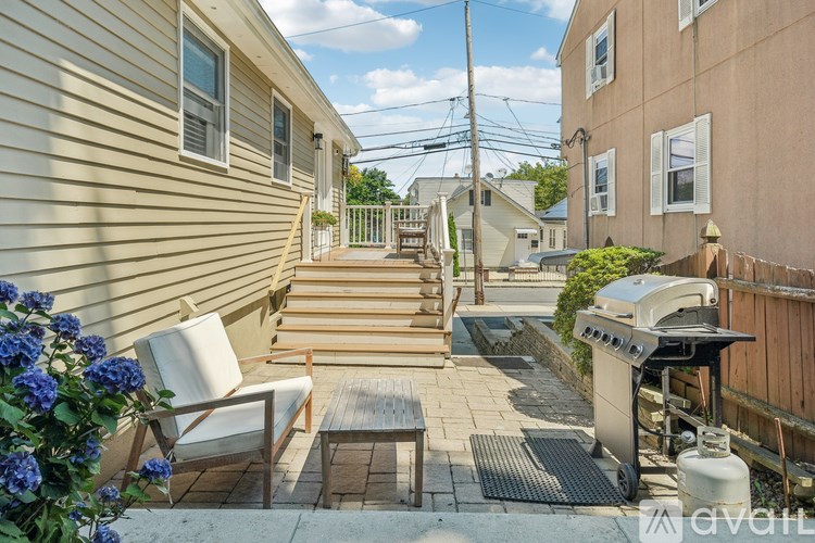 A patio with a table, chairs, and a grill.