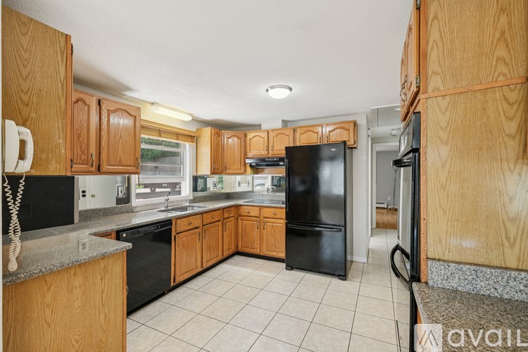 A kitchen with black appliances and wooden cabinets.