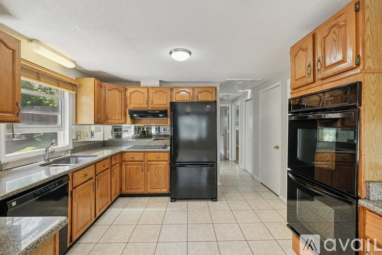 A kitchen with wooden cabinets and black appliances is available for rent.