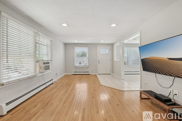 A spacious room with wooden flooring and white walls.