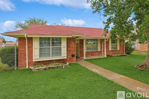 A red brick house with a red roof and a green lawn.
