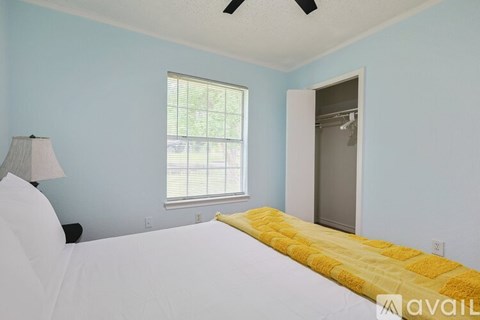 A bedroom with a bed, lamp, and window.
