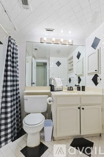 A black and white bathroom with a toilet, sink, and mirror.