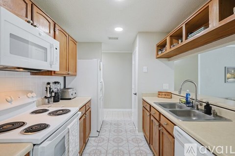 A kitchen with white appliances and wooden cabinets.