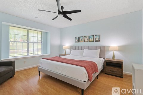 A bedroom with a bed, nightstand, and a fan.