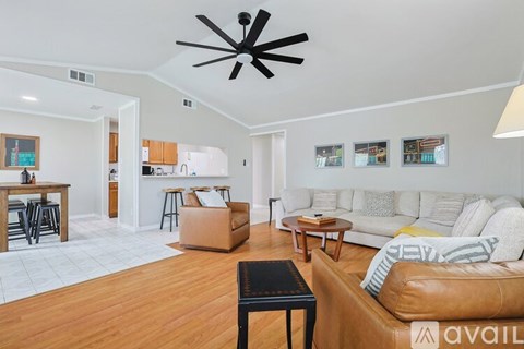 A living room with a brown leather couch and a ceiling fan.