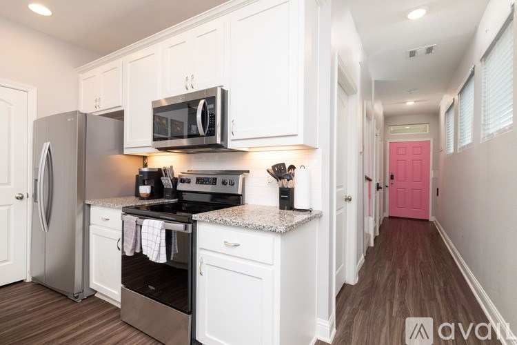 A kitchen with white cabinets and a black microwave above the stove.