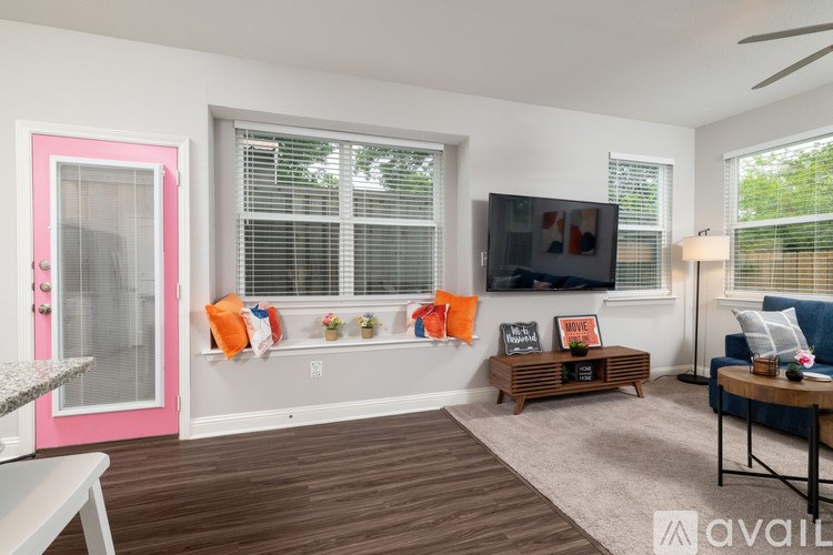 A living room with a pink door and a wooden floor.