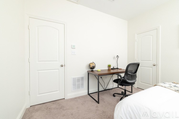 A room with a desk, chair, and bed.