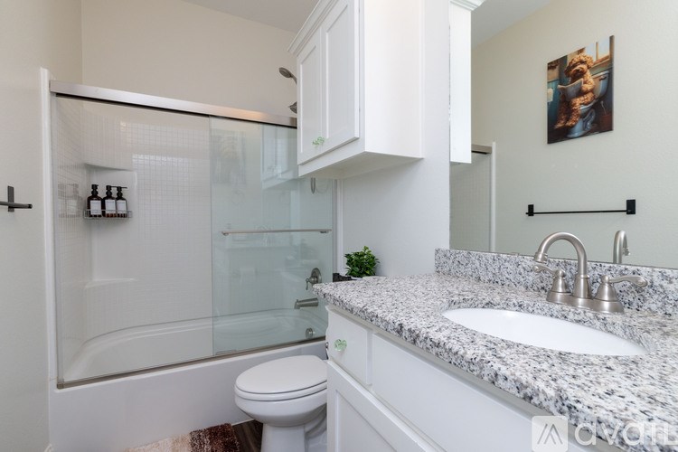A bathroom with a white toilet, a sink, and a glass shower door.