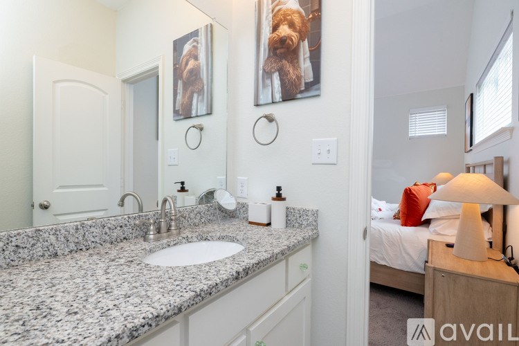 A bathroom with granite countertops and a bedroom in the background.