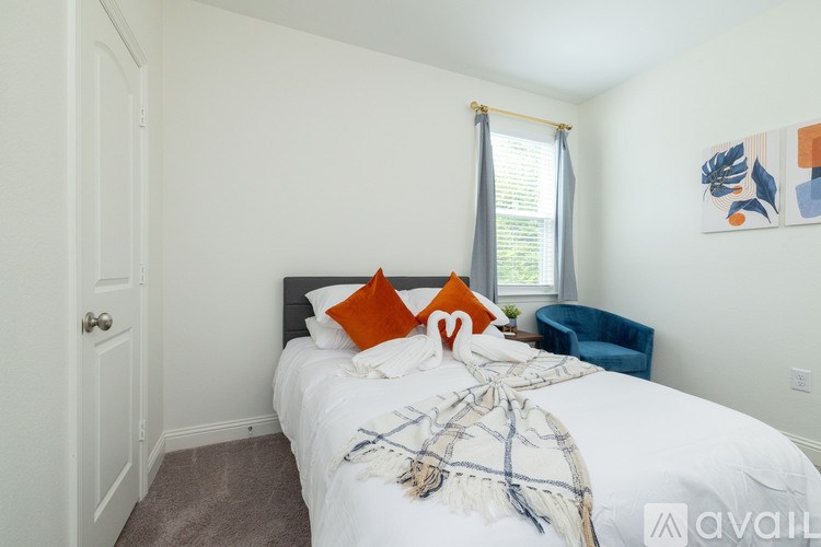 A bedroom with a white bed and a blue chair.