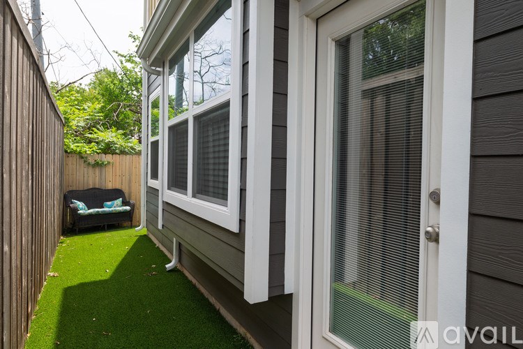 A small patio area with a white door and a green artificial grass area.