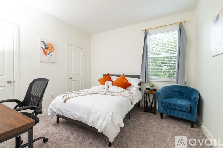 A bedroom with a bed, chair, and window.