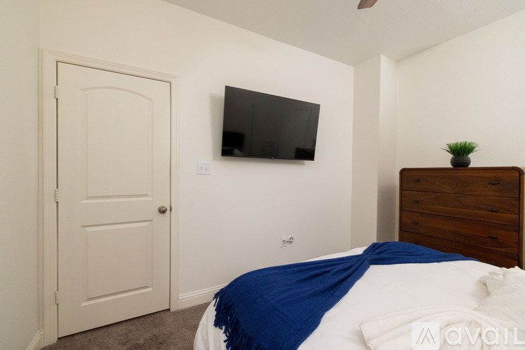 A bedroom with a bed, a dresser, and a television.