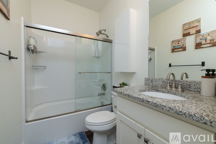 A bathroom with a glass shower door, a white toilet, and a granite countertop.