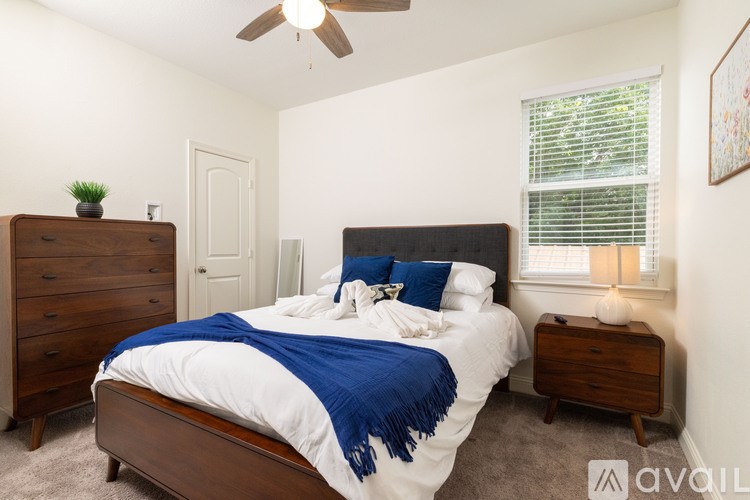 A bedroom with a bed, dresser, and ceiling fan.