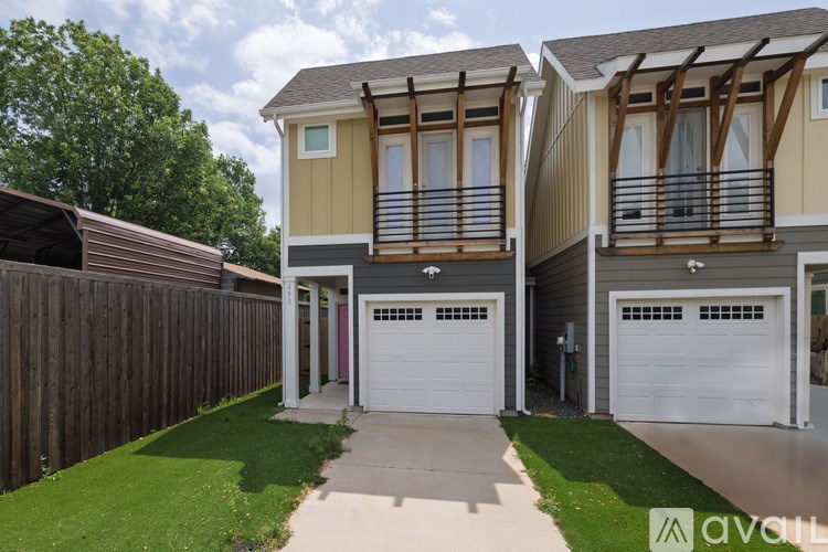 A row of houses with garages and green lawns.