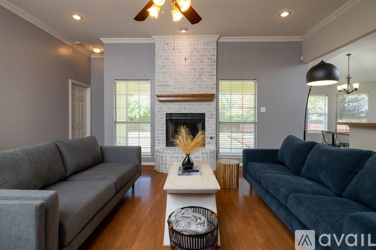 A living room with a grey couch, a white coffee table, and a fireplace with a white brick wall.