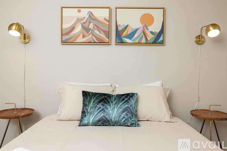 A bedroom with a bed, two lamps, and two framed pictures on the wall.