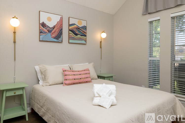 A bedroom with a bed, two lamps, and two pictures on the wall.