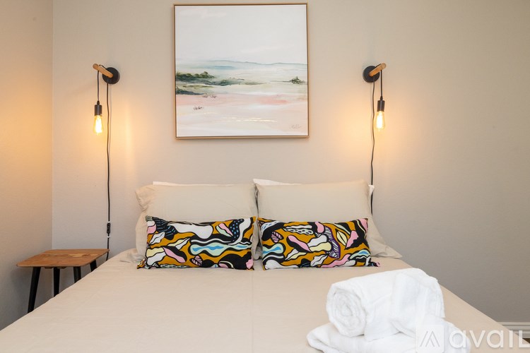 A bedroom with a bed, two lamps, and a painting on the wall.