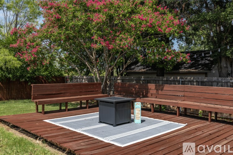 A wooden deck with a bench and a table surrounded by greenery.