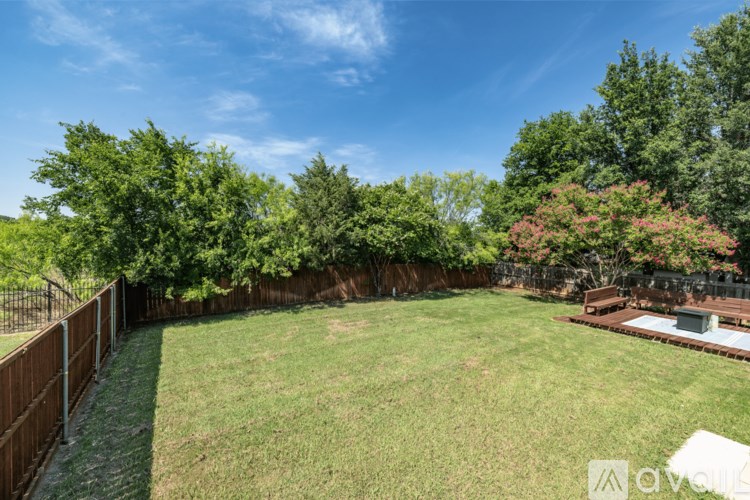 A backyard with a wooden fence and a green lawn.