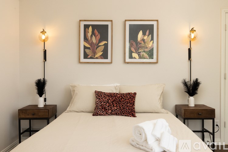 A bedroom with a bed, two lamps, and two framed pictures on the wall.