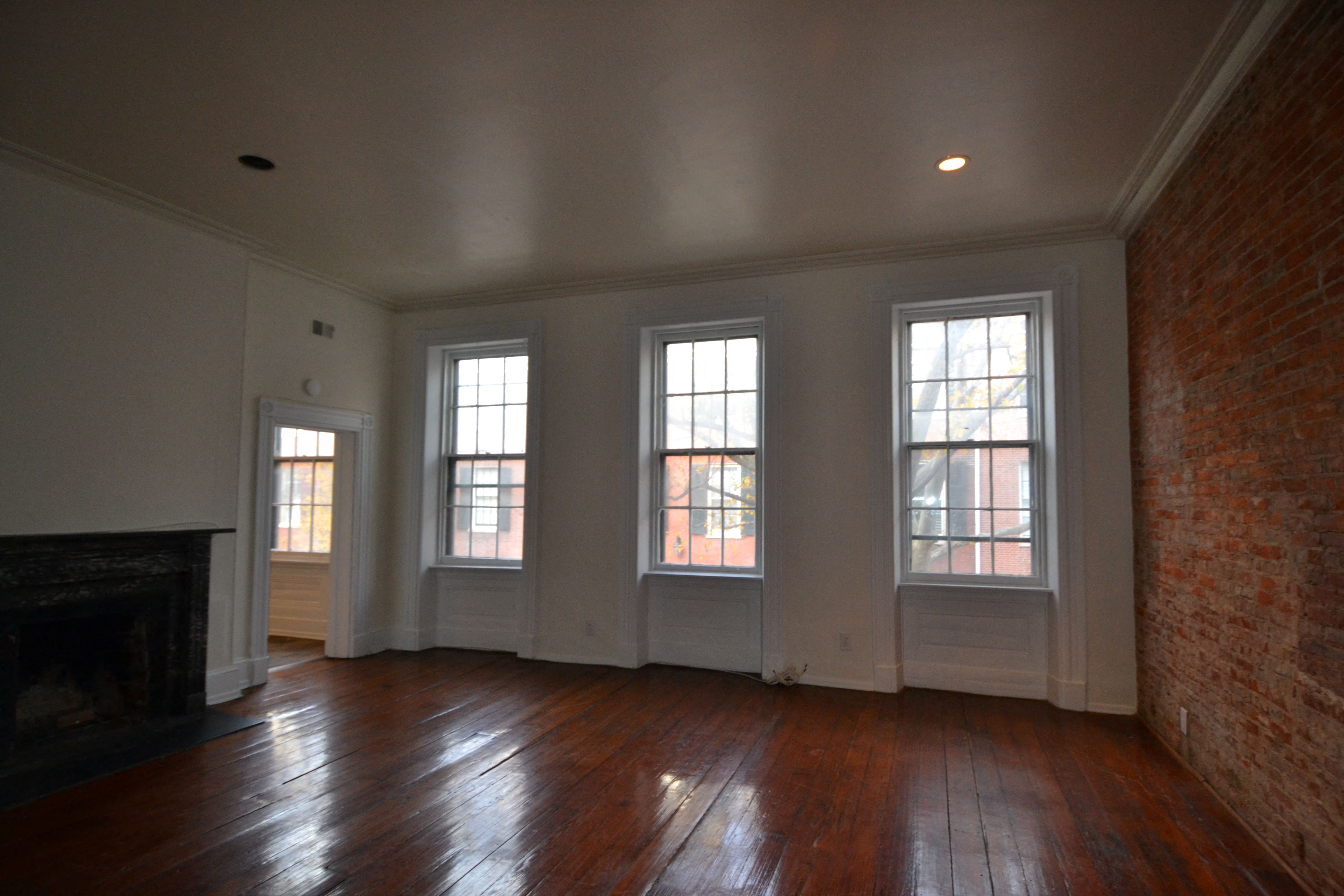 an empty living room with a fireplace and four windows