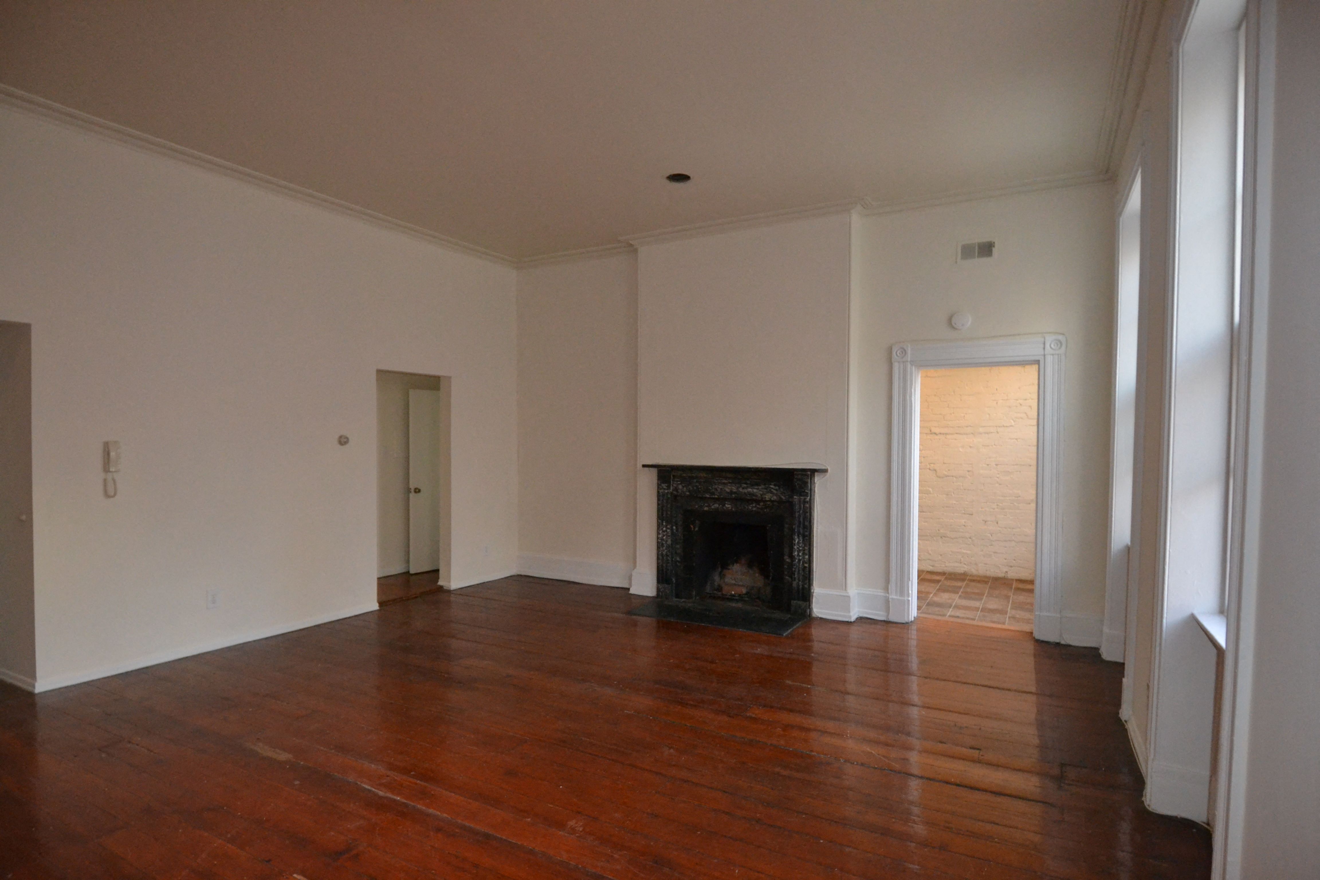 an empty living room with a fireplace and wooden floors