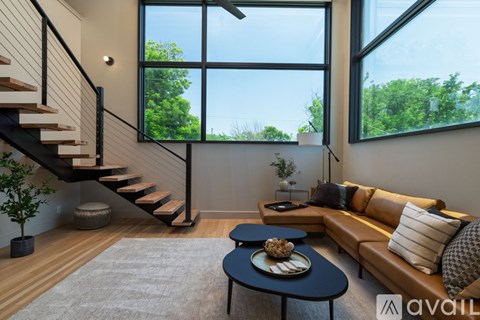 A living room with a couch, coffee table, and staircase.